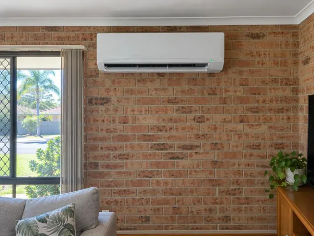 Split system on a brick living room wall above a lounge, louvre open and running in Mermaid Waters